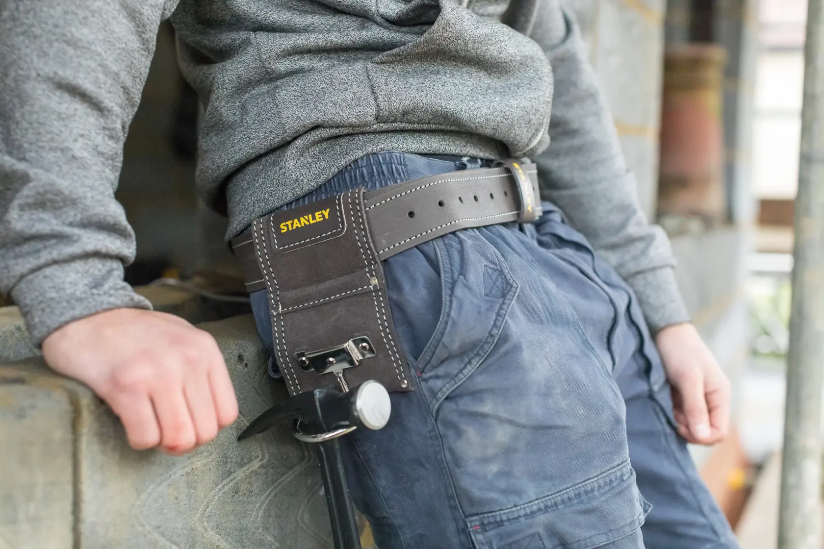 STANLEY STST1-80117 leather hammer holder attached to belt, outdoor work setting, product photography.