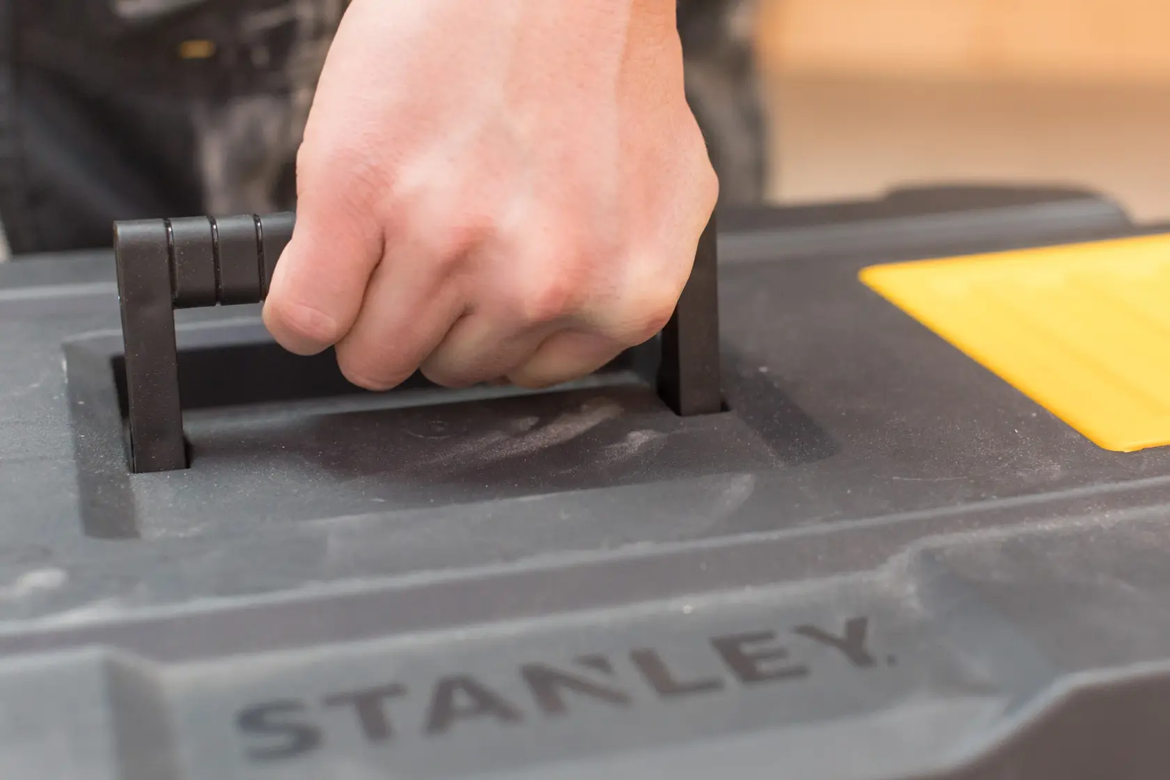 STANLEY STST1-80150 toolbox close-up, hand holding black handle, yellow accent visible.
