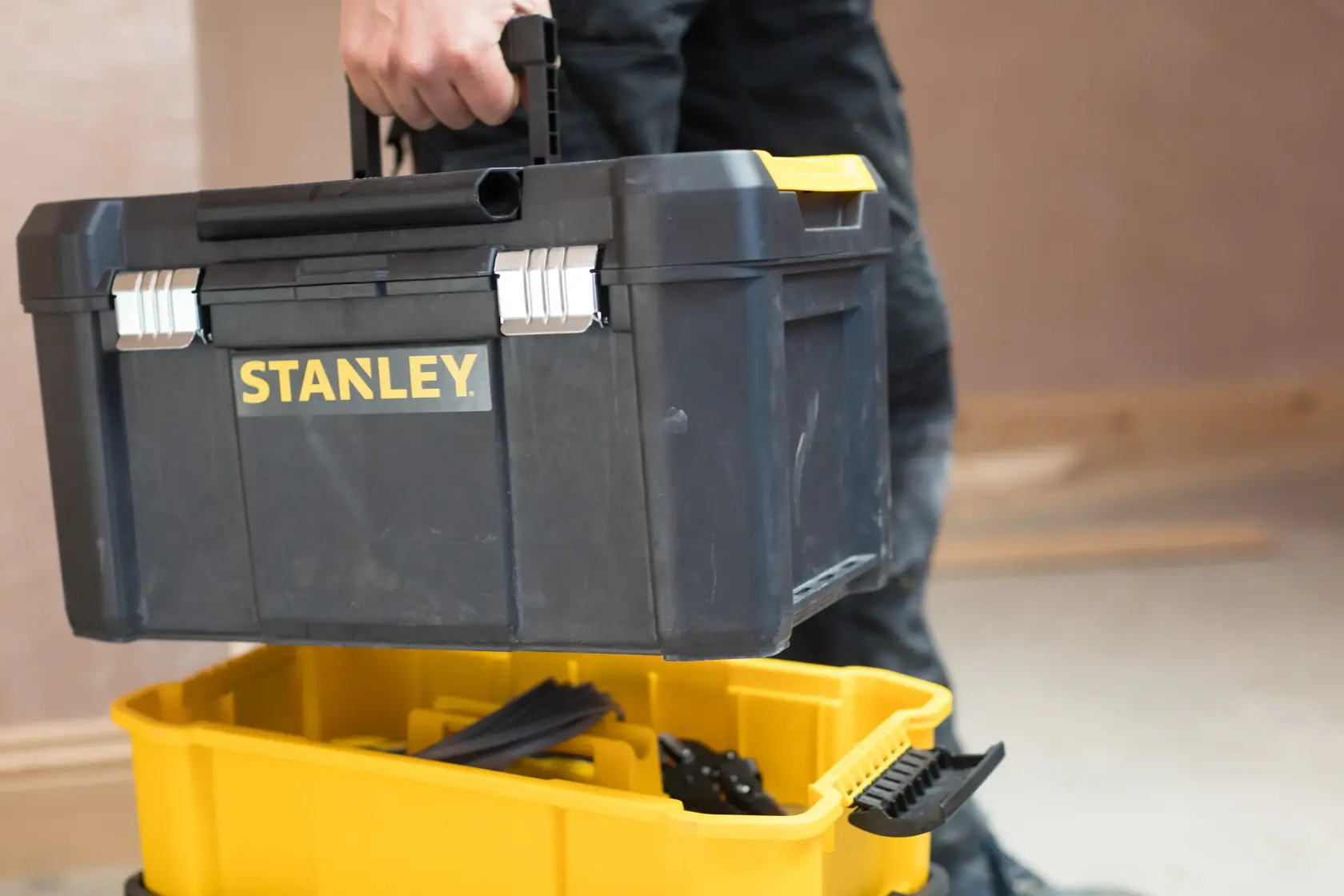 STANLEY STST1-80151 black toolbox with yellow accents, carried by hand, photography product category.