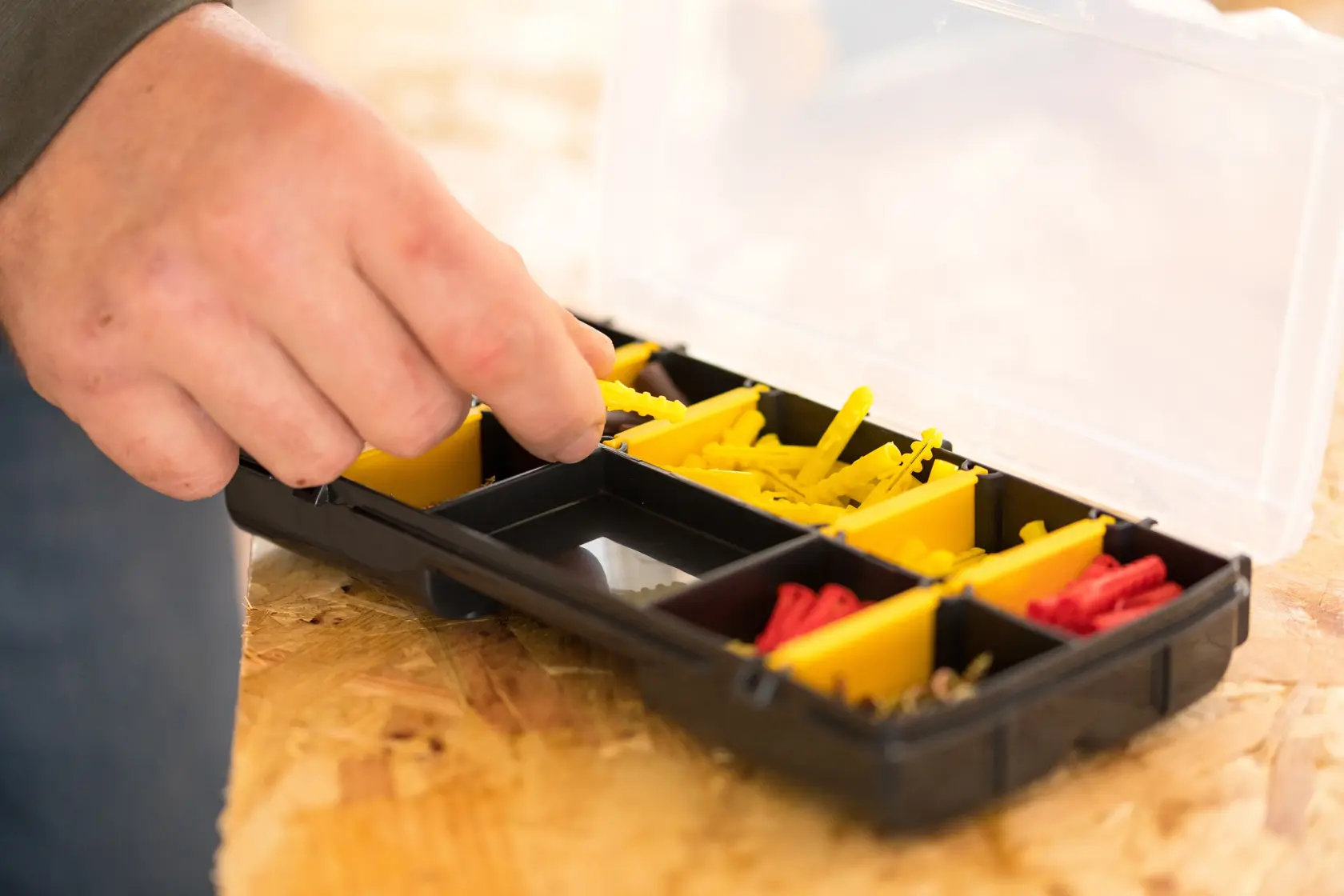STANLEY STST81679-1 organizer box with yellow and red compartments, hand picking item, top view.