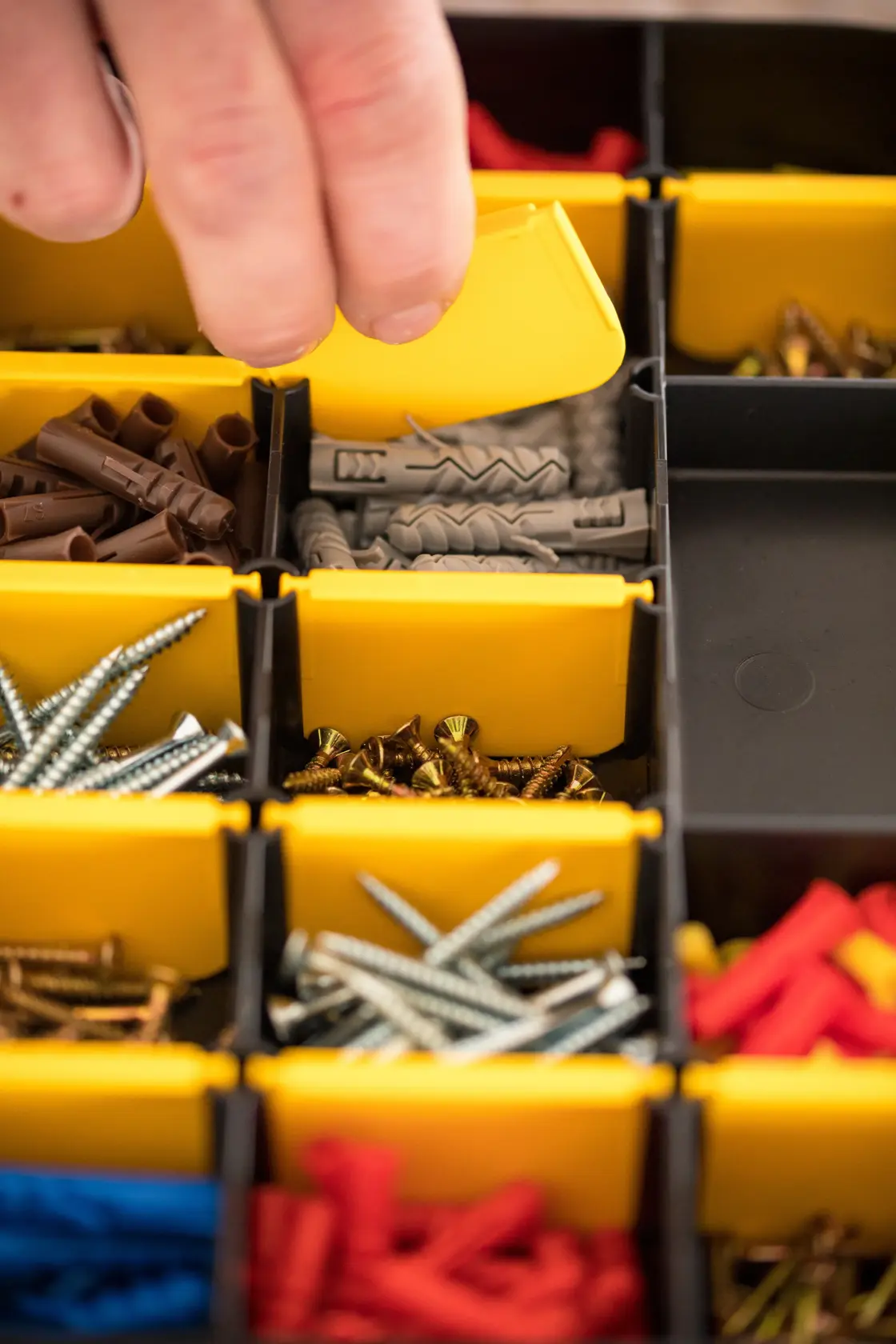 STANLEY STST81680-1 photography of hand opening yellow bin with assorted screws and wall plugs.