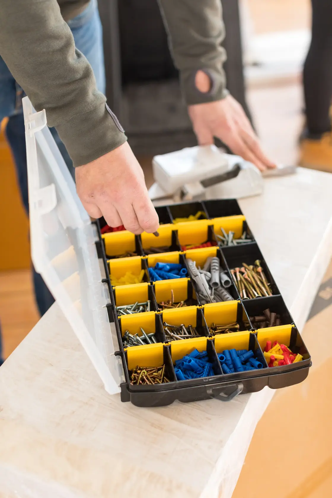 STANLEY STST81681-1 organizer box with yellow dividers holding assorted screws and wall plugs, open on a table.