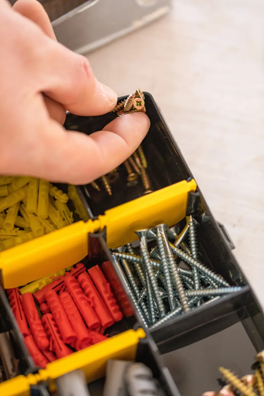 STANLEY STST81681-1 organizer with hand picking screws, assorted wall plugs and fasteners visible.