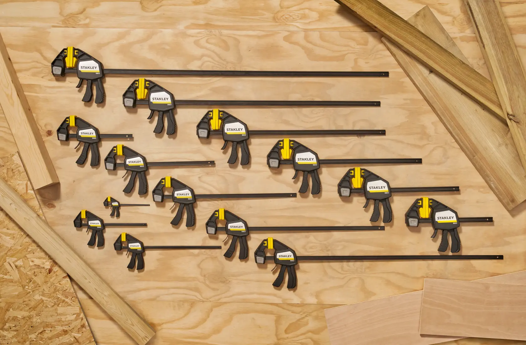 STANLEY FMHT83270-0 bar clamps set, various sizes, black and yellow, top-down view on wooden surface.
