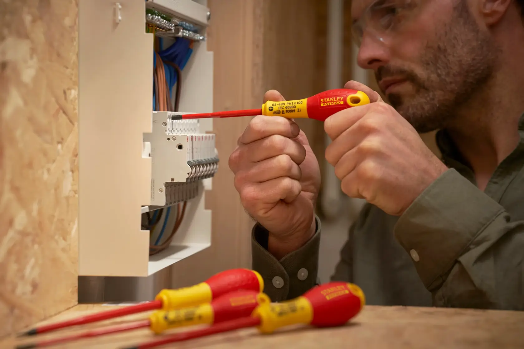 Photo of Stanley XTHT0-62692 insulated screwdriver in use on electrical panel, with two others on table.